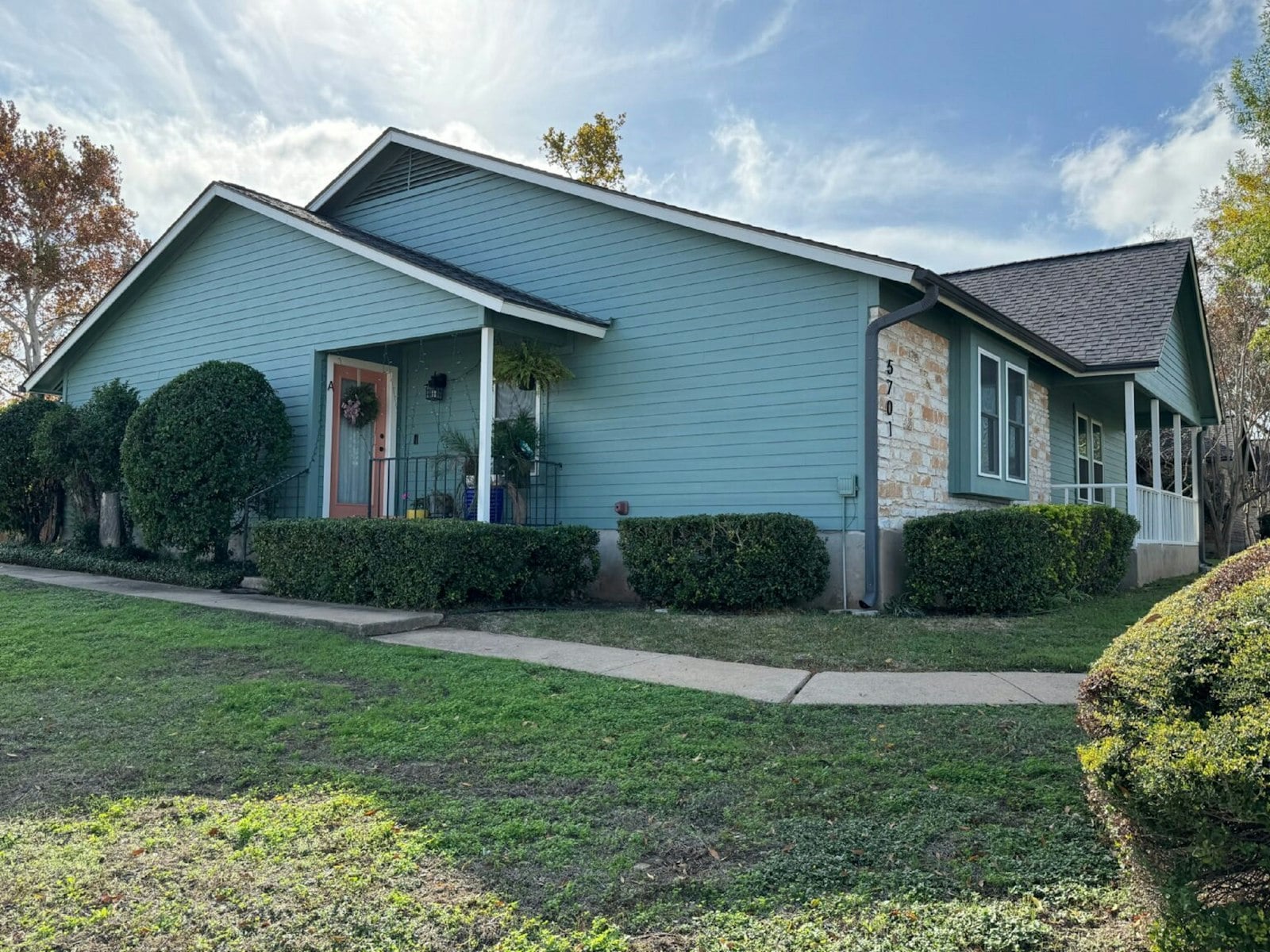 Single-story teal house with stone accents and a green lawn