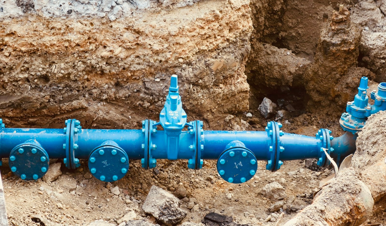 Blue water main pipes and valves in an open trench