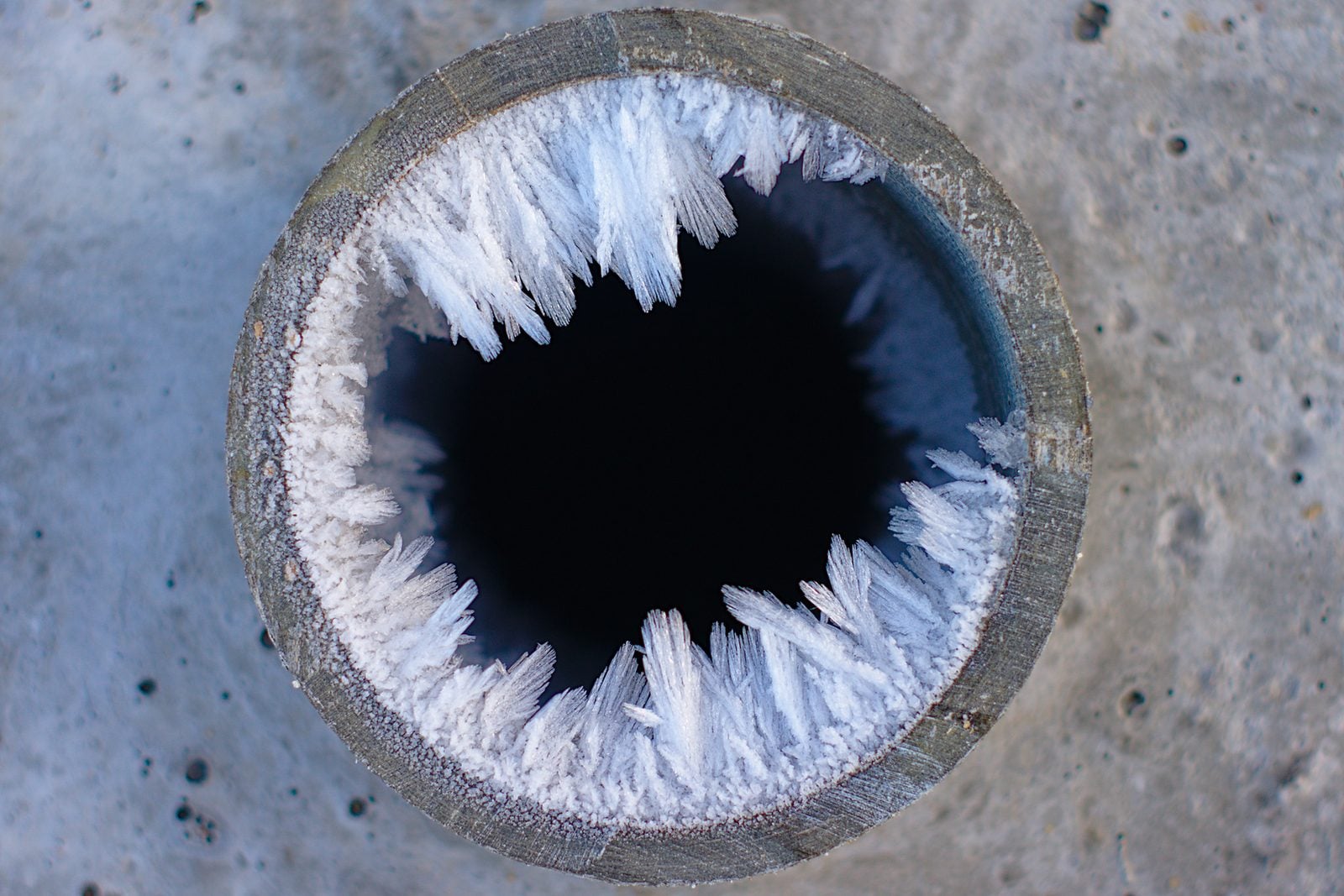 Ice crystals forming inside a pipe opening in concrete