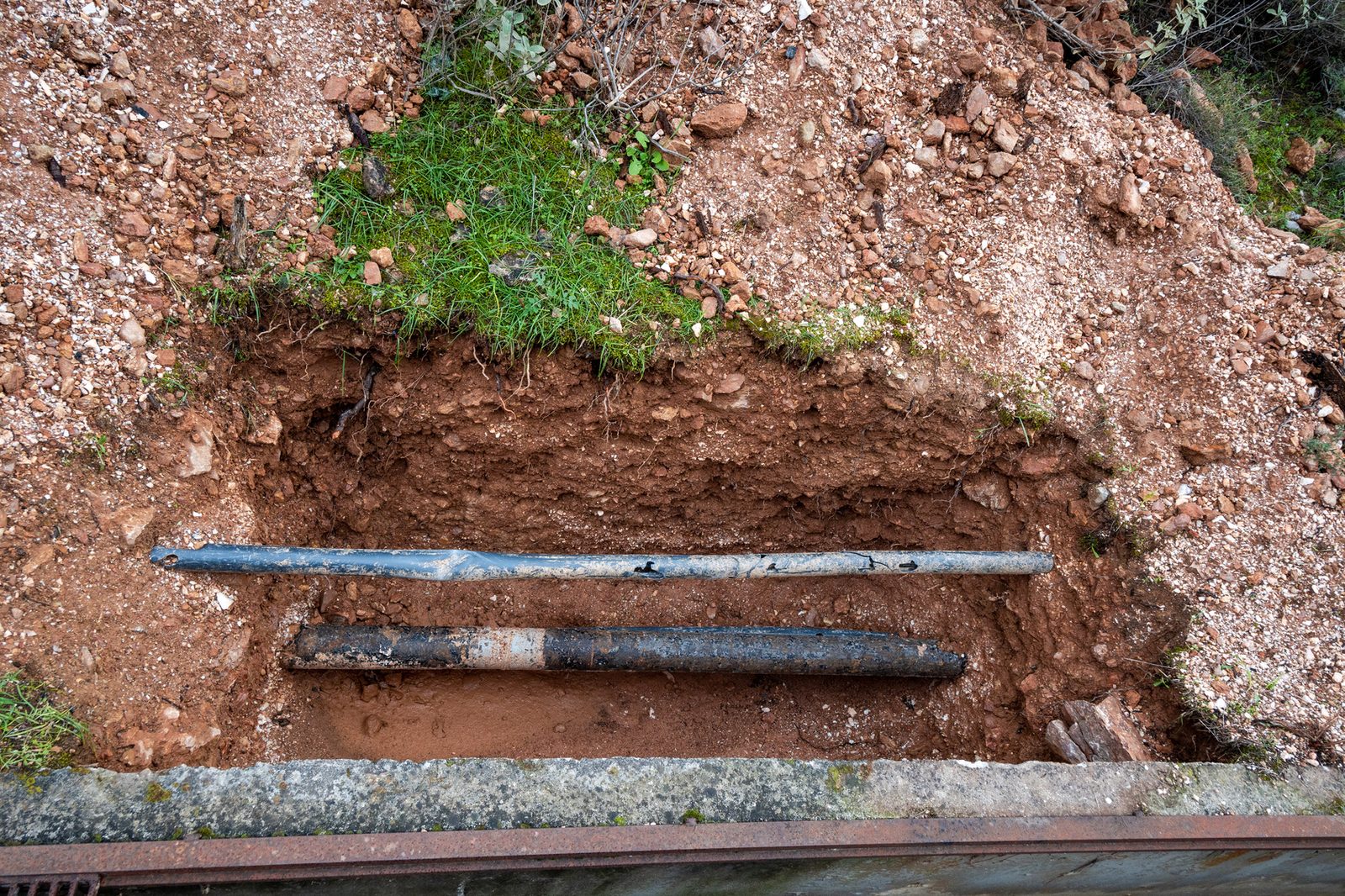 Broken water pipes exposed in a dug trench outdoors